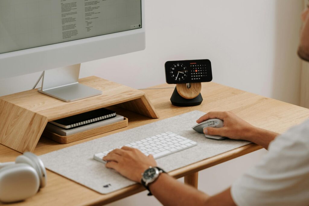 A clean and modern desk setup featuring a computer, clock, and accessories in a home office.