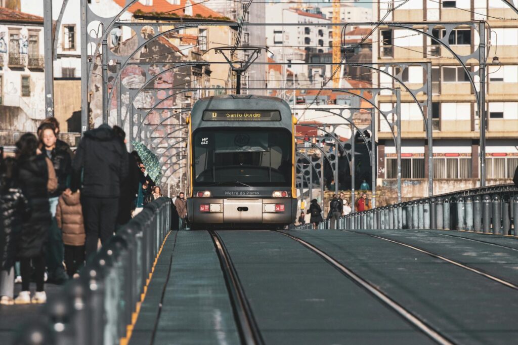 A metro tram traveling on the Ponte Luís I Bridge in Porto, Portugal, surrounded by urban architecture.