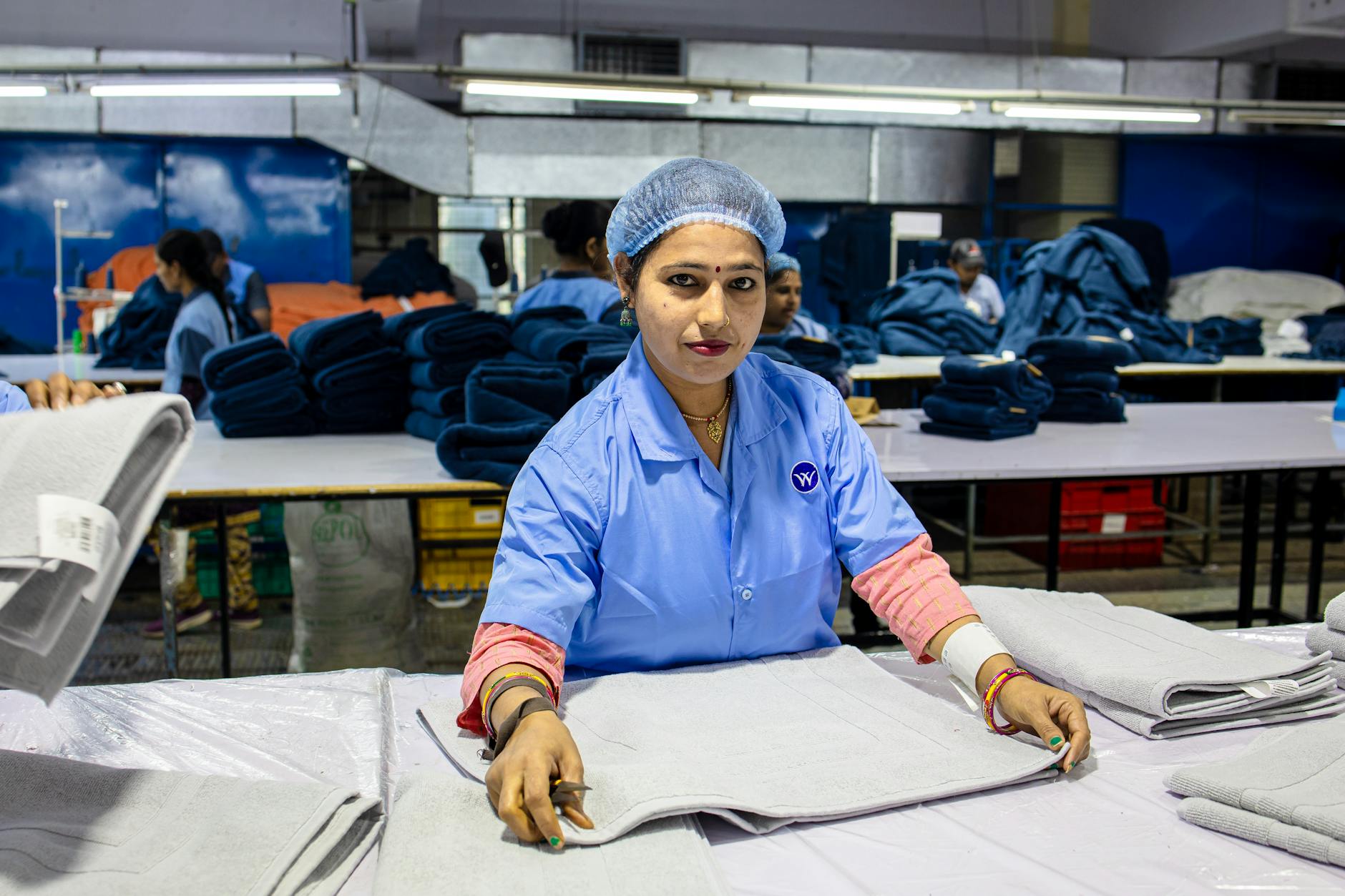 Image of a female textile worker folding fabrics in an industrial setting.