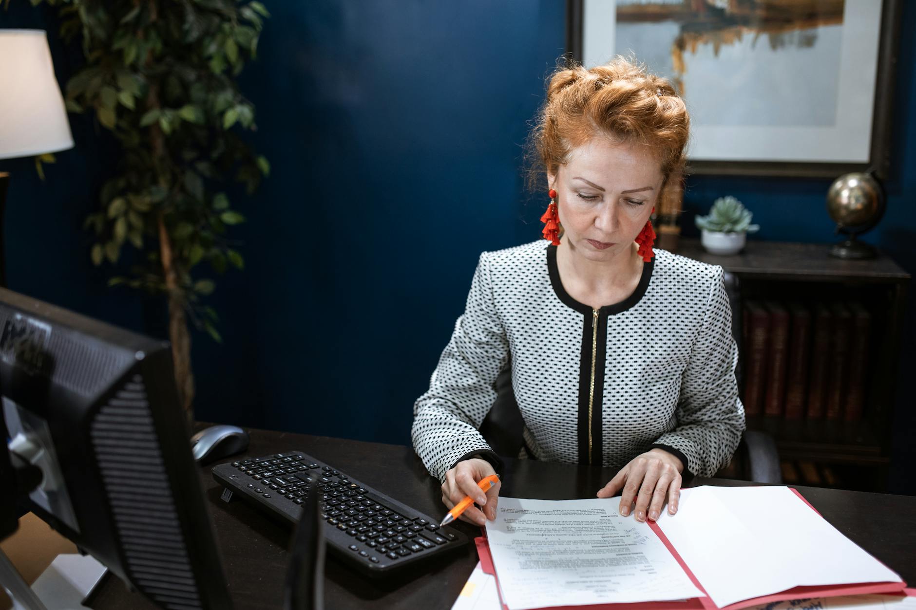 A focused woman working on paperwork in a modern office environment.