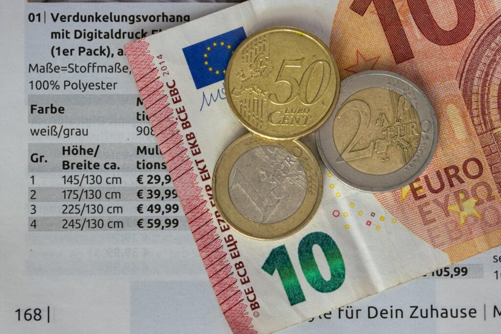 Euro coins and bills on a price list, symbolizing finance and economy.