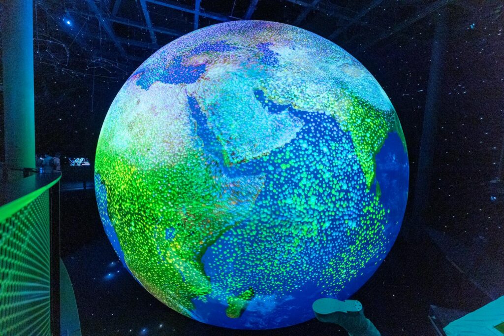 Glowing digital globe display at night in Dubai Expo, showcasing illuminated continents.