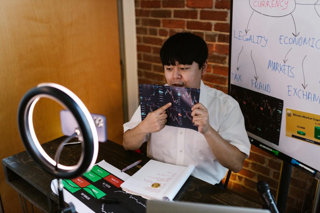 Man analyzing cryptocurrency data with ring light and flip charts in a home office.