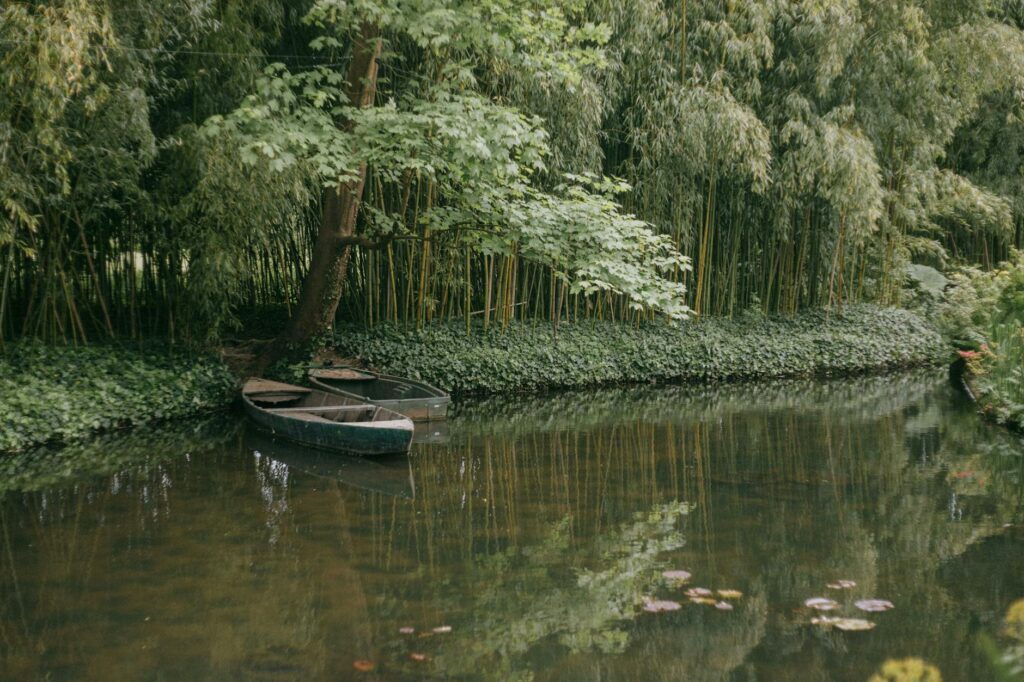 Serene view of small boats on a quiet pond surrounded by lush greenery in Giverny, France.