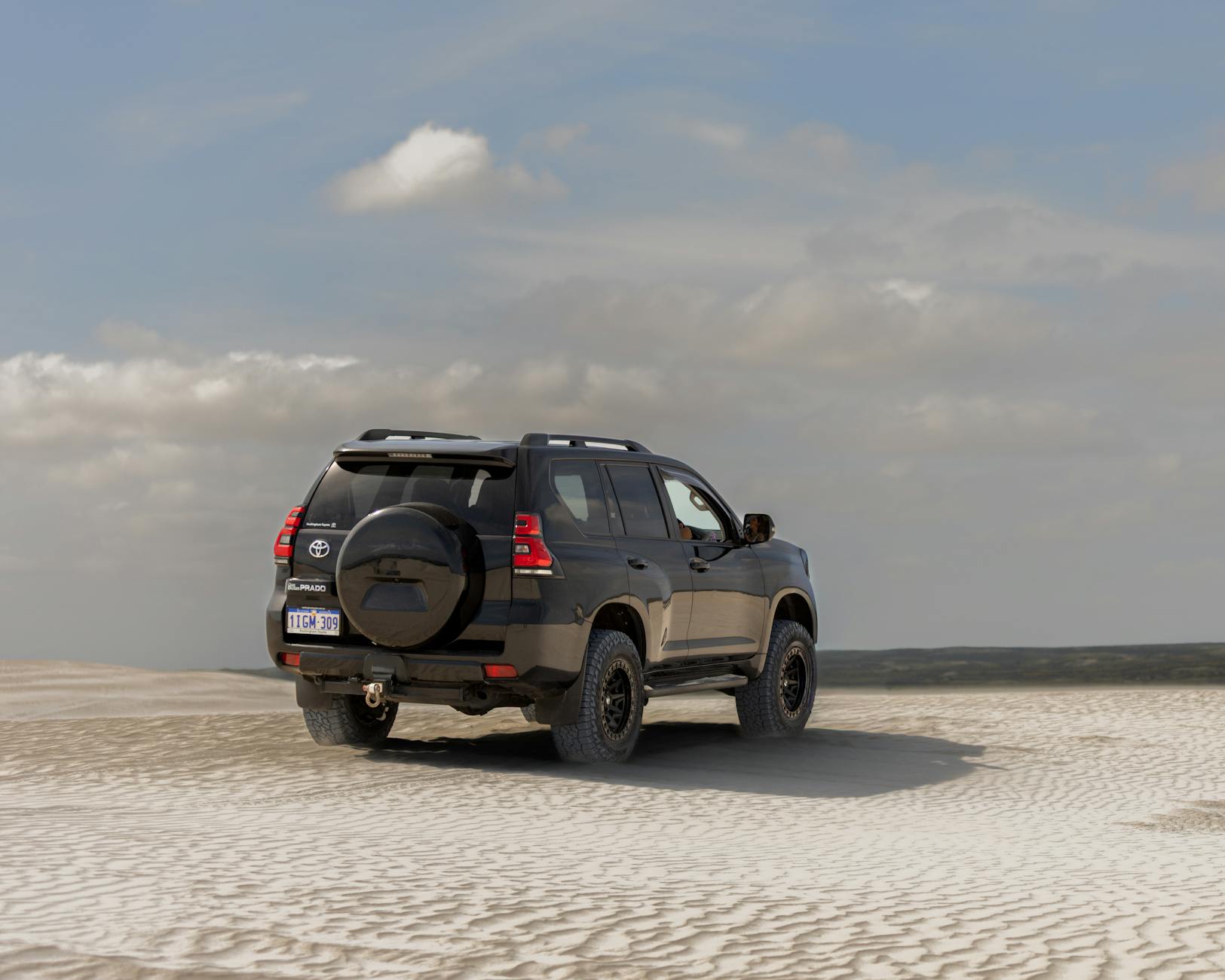 Toyota Prado navigating the sandy dunes of Lancelin, Western Australia, under a clear sky.