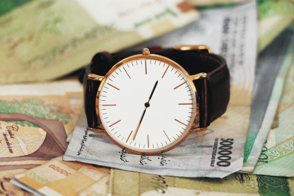 A sophisticated wristwatch resting atop Iranian rial notes, symbolizing time's value in Tehran.